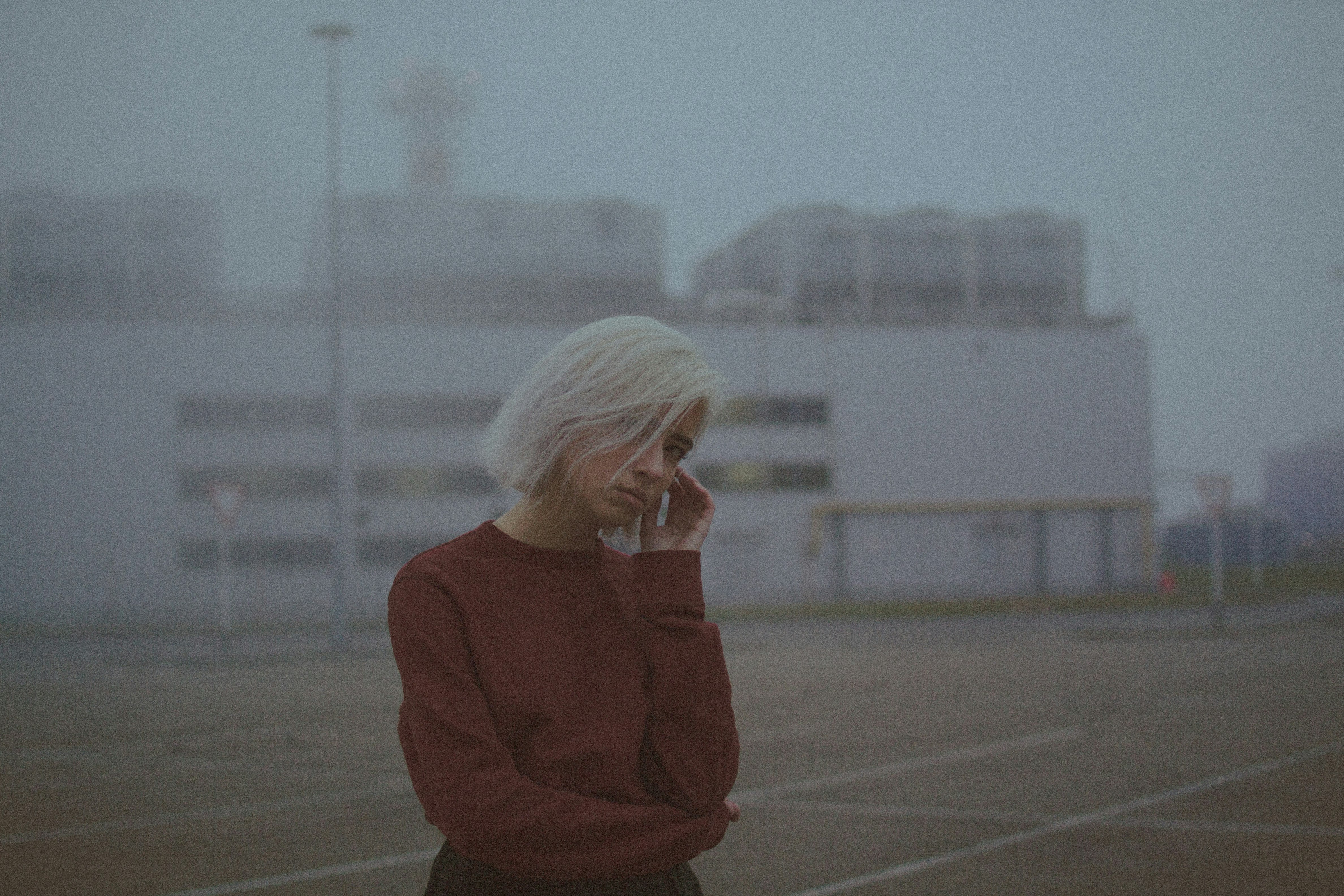 woman in red sweater standing on gray concrete floor during daytime